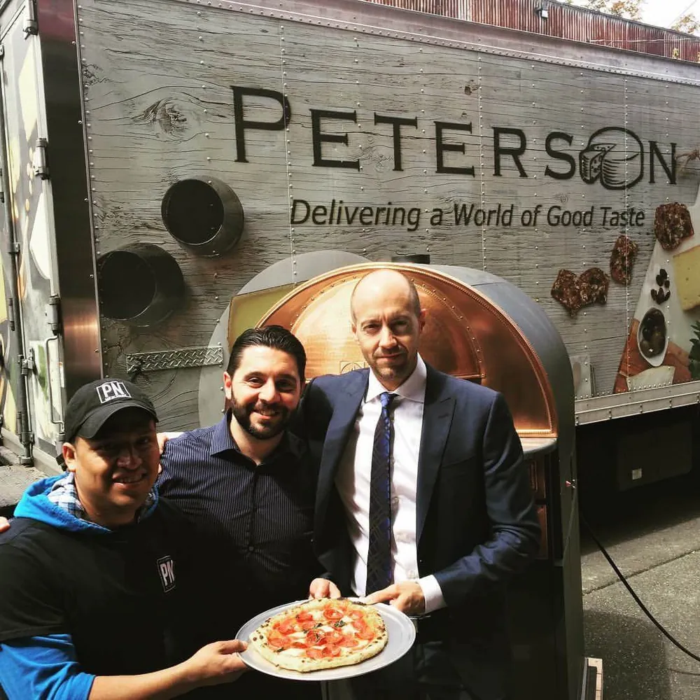 Giacomo Baldi con socios en un evento de pizza de Peterson